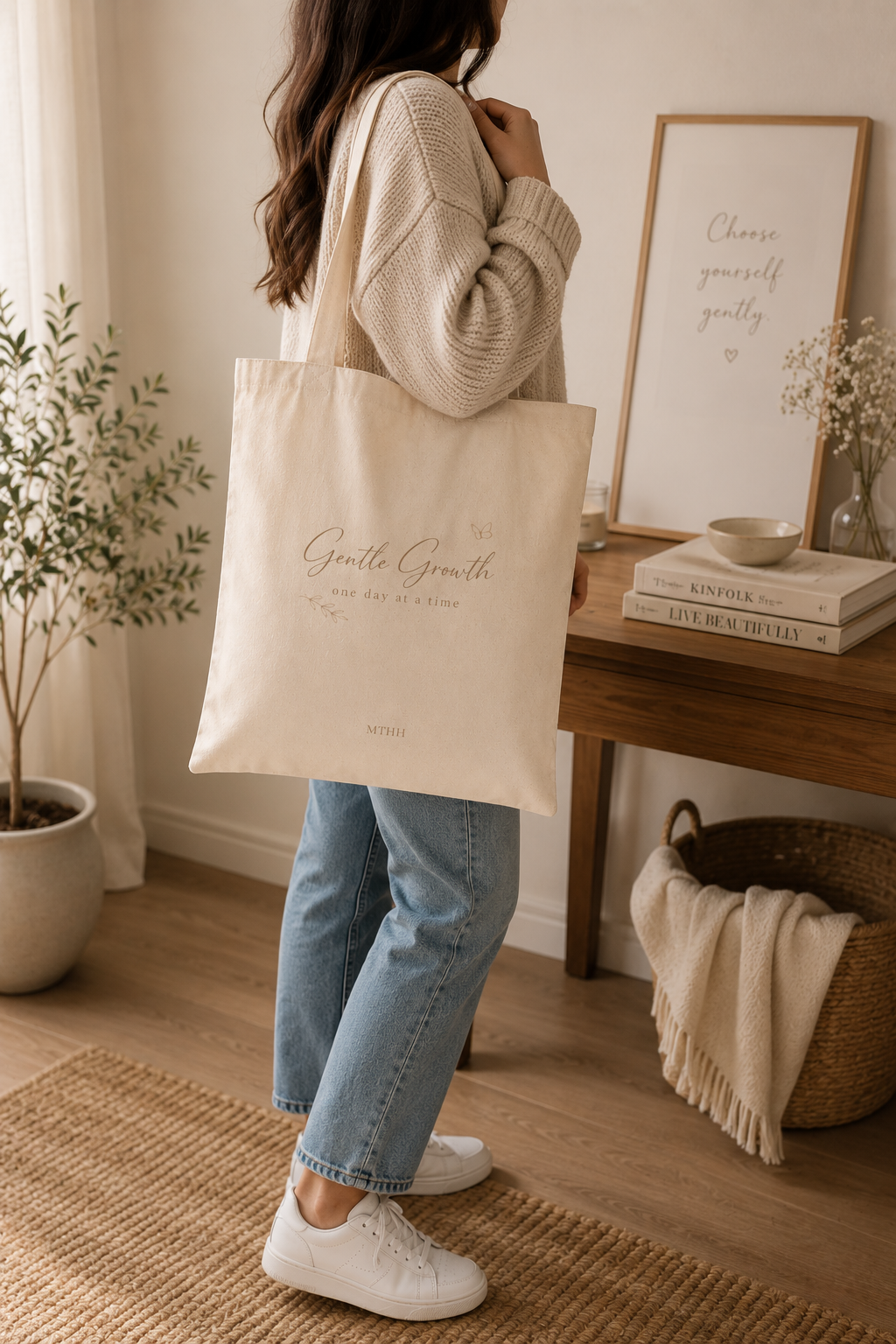 Woman carrying the Gentle Growth beige canvas tote bag in a cozy minimalist home, showing the bag's everyday size and style.